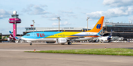 Flugzeug von TUI fly auf dem Vorfeld, im Hintergrund sieht man das Flughafengebäude und den Eurowings-Tower