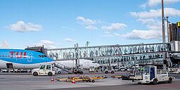 Vorfeldbild mit einer blauen B737 und einer Fluggastbrücke